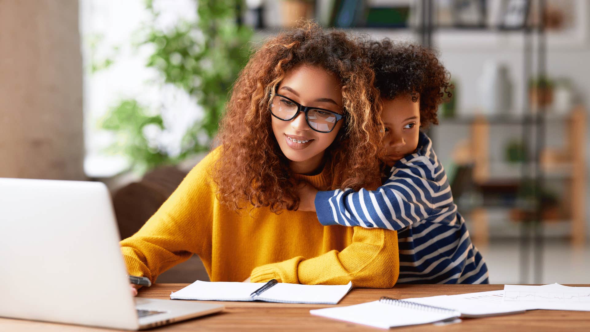 Parent does job while child hold her