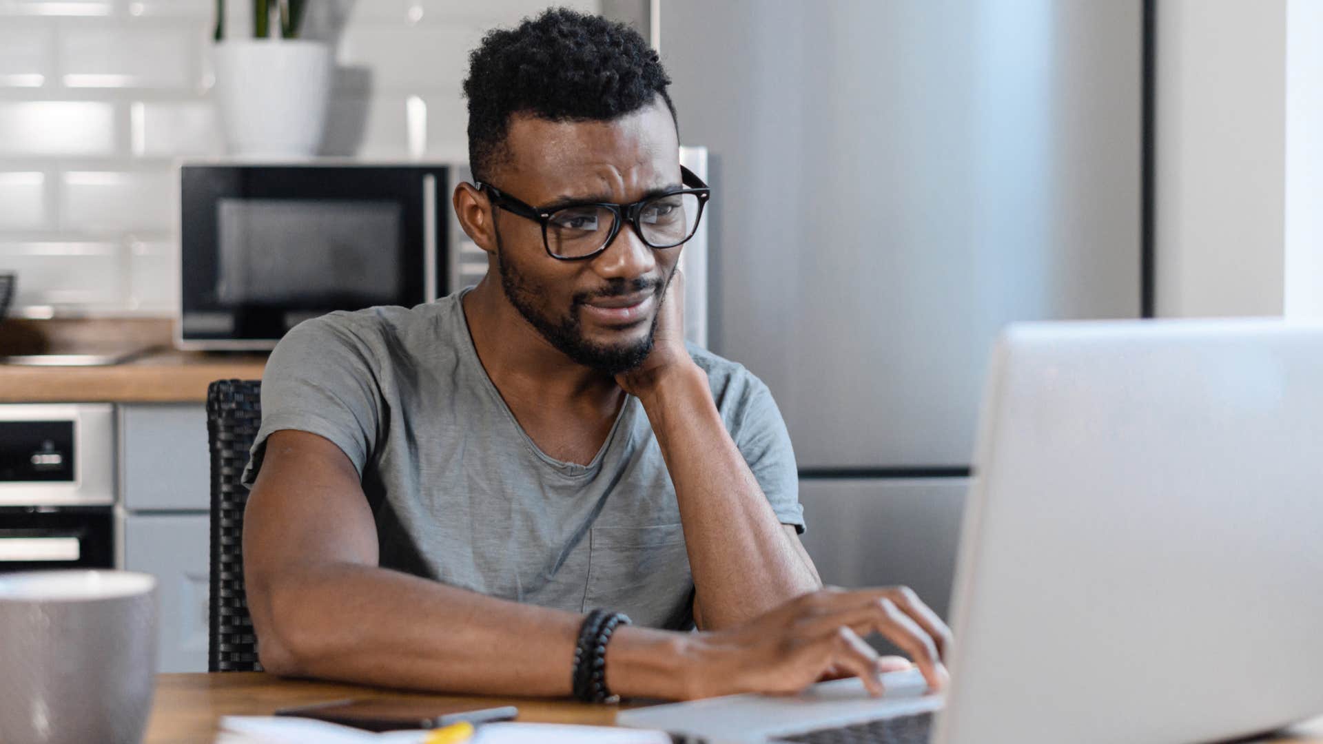 Upset Gen Z man thinking about ai writing technology devaluing freelance work.