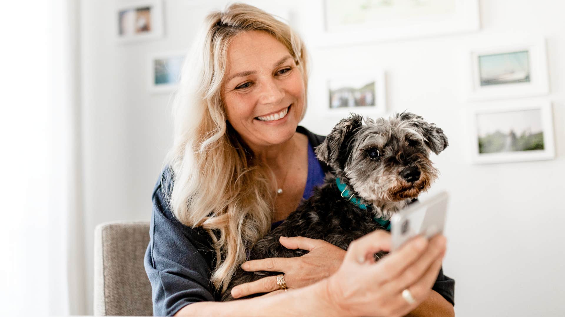 woman sitting in front of framed photos holding dog