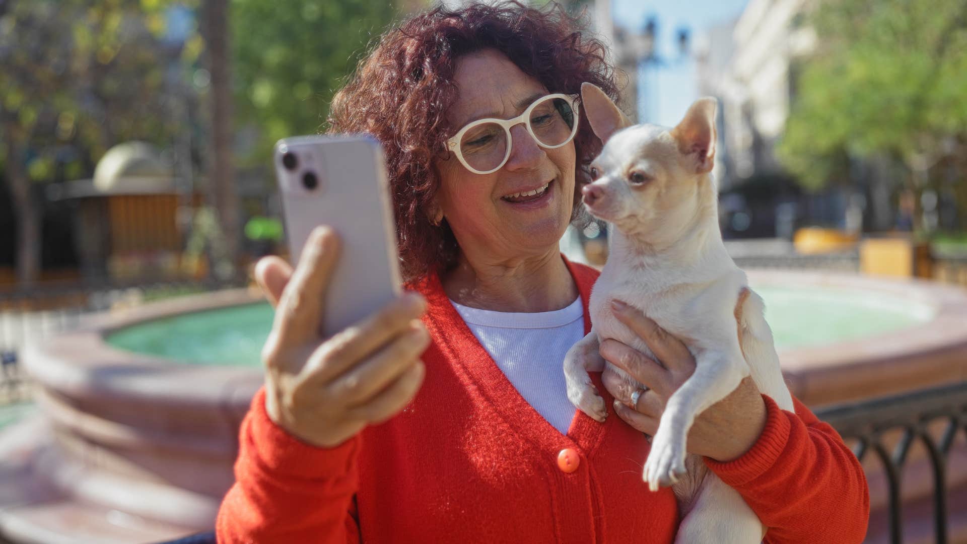 woman holding dog up to phone