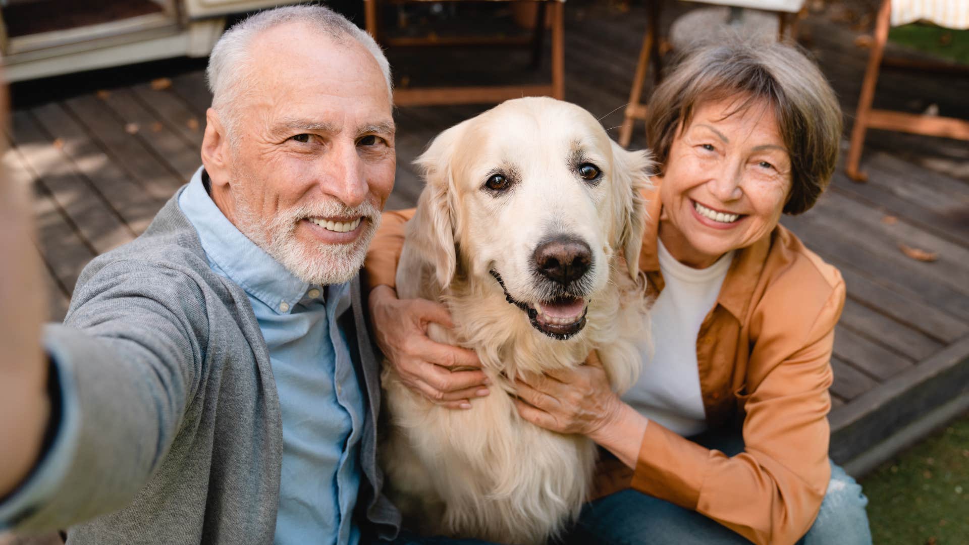 boomer grandparents hugging dog and smiling taking selfie
