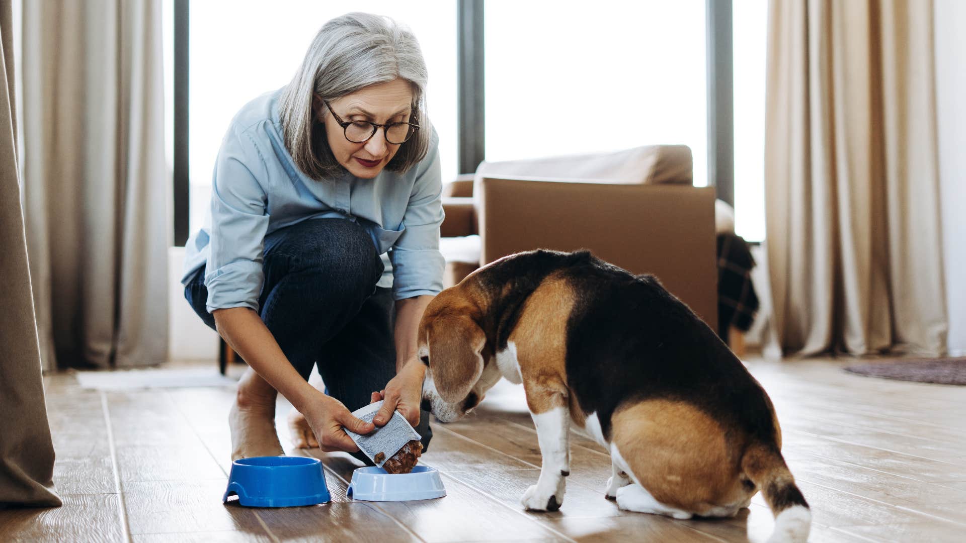 boomer woman feeding her dog at home
