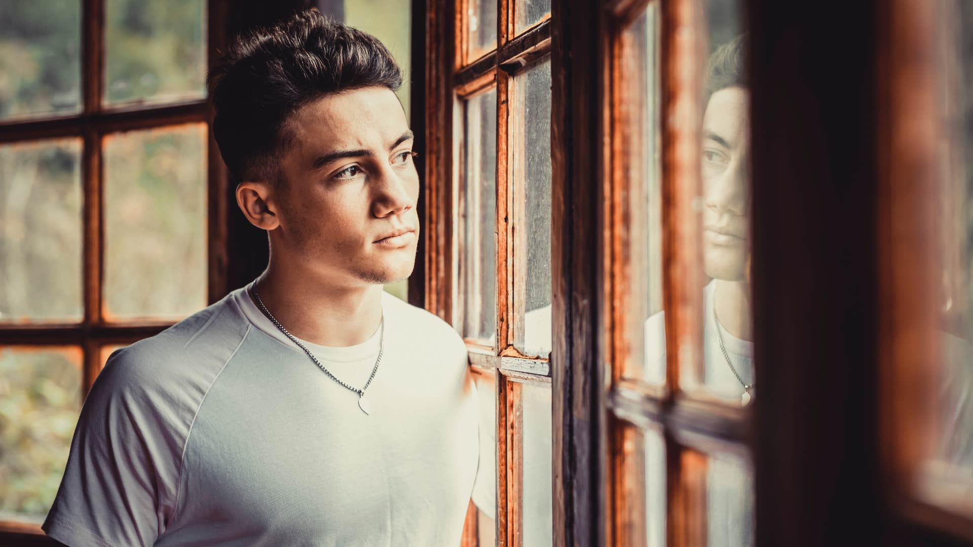 young man looking out the window thinking