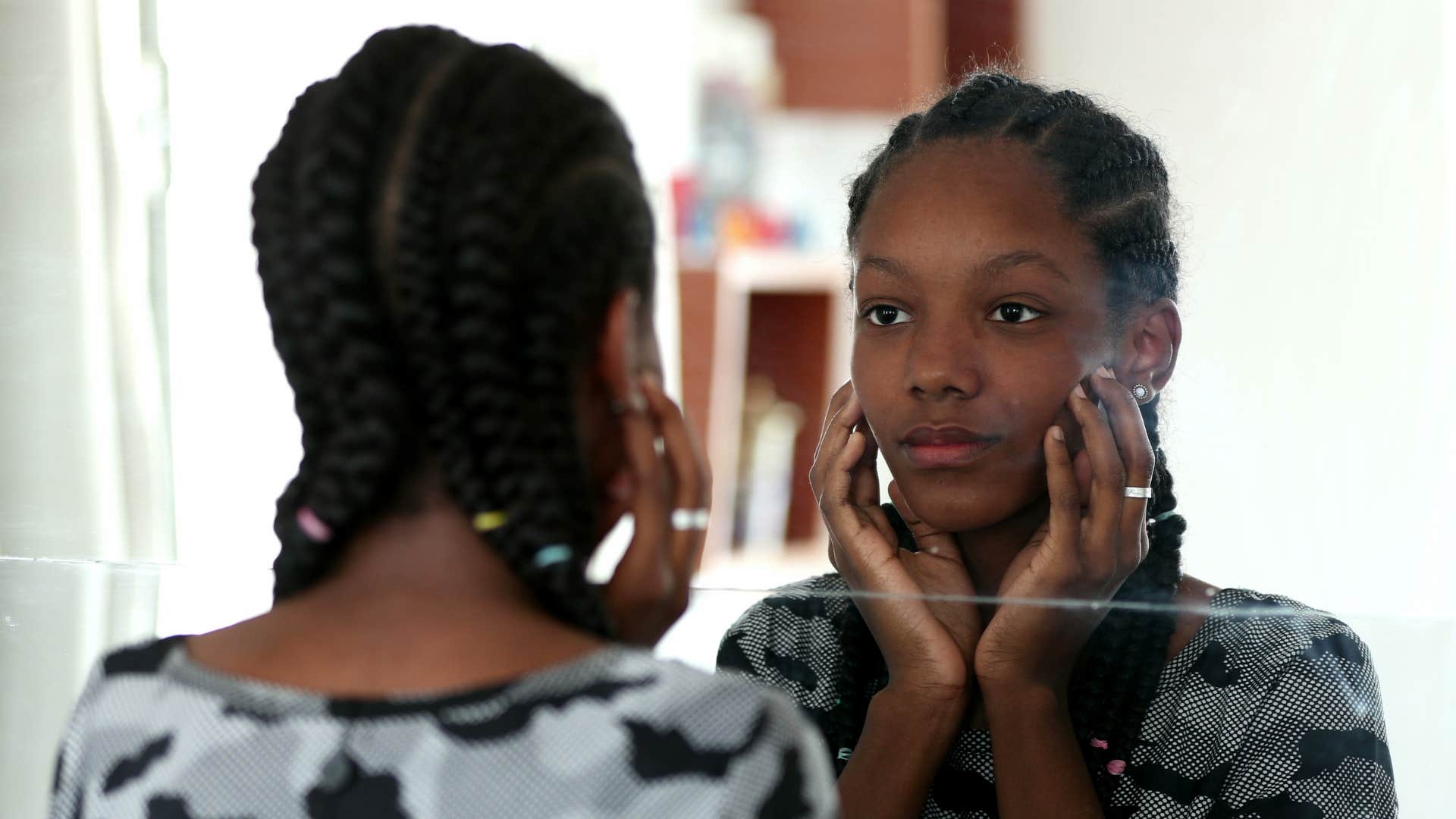 sad teen girl judging herself in the mirror