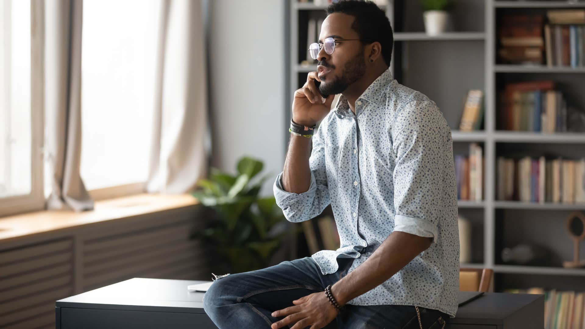 man in glasses always being the first one to contact first as he calls someone and sits on the desk