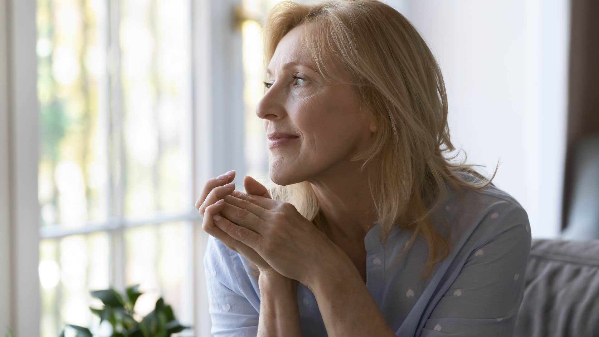 Woman with clarity on her needs smiling and looking out a window.