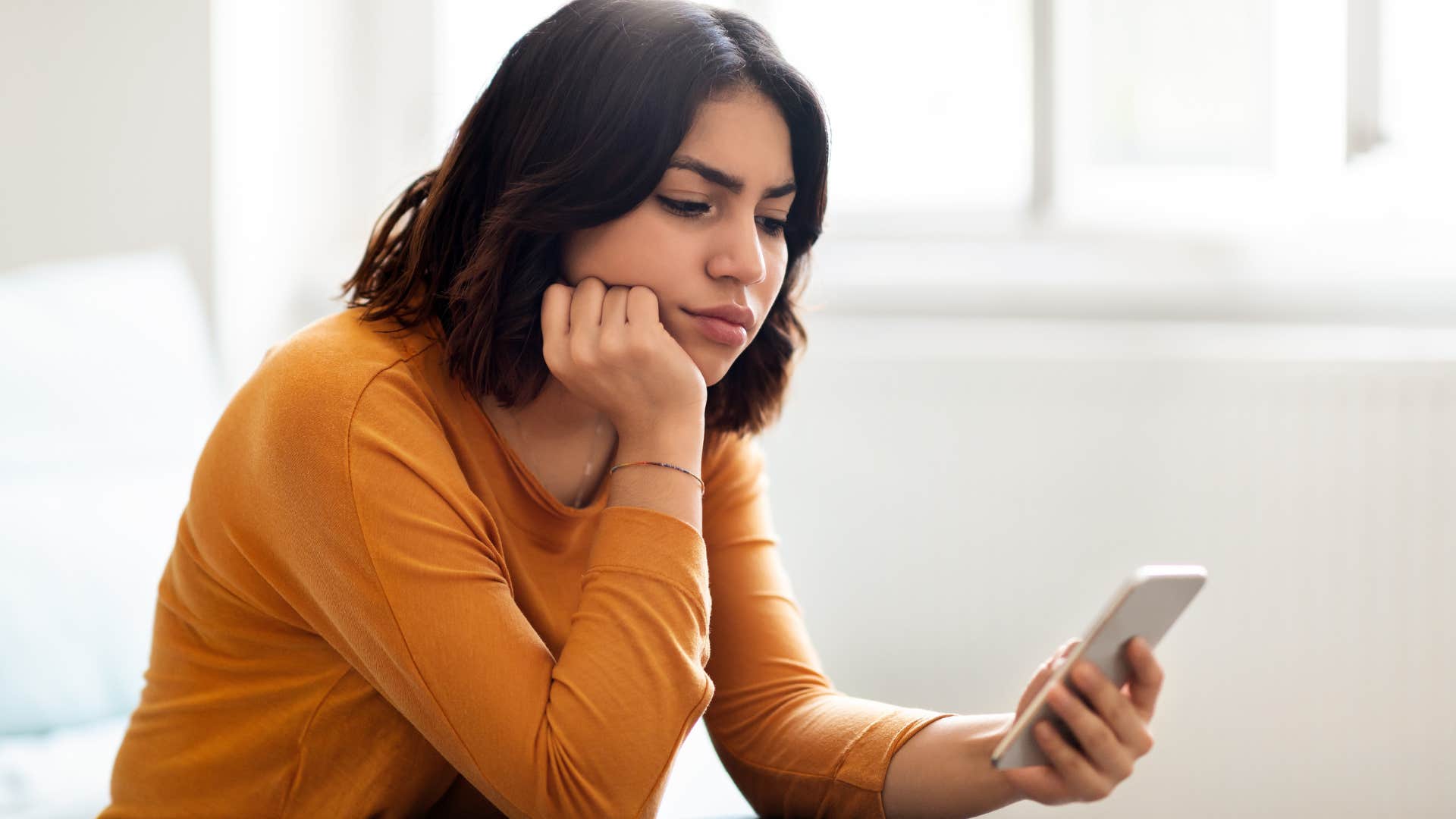 Woman who's drifting away from certain people looking at her phone.