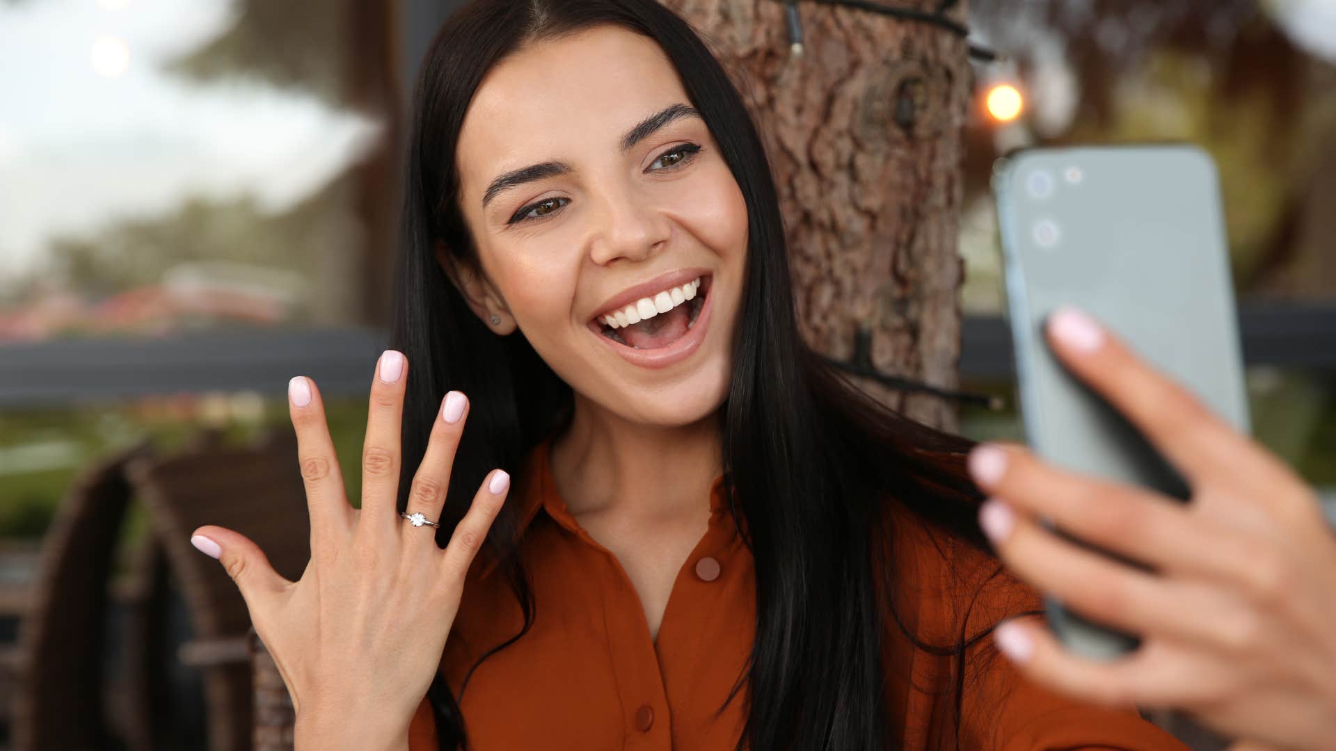Showing woman with realized manifestations smiling and holding up her engagement ring