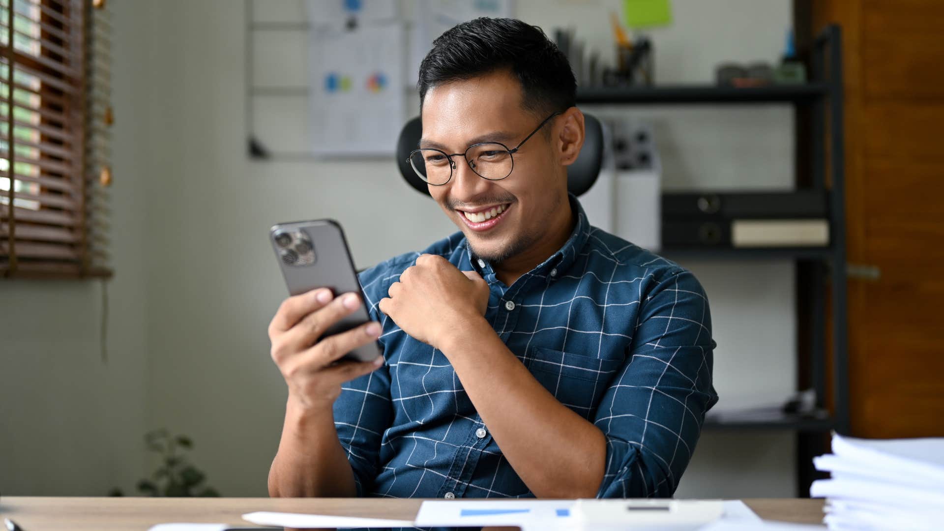 Man smiling at his phone over new unexpected opportunities.