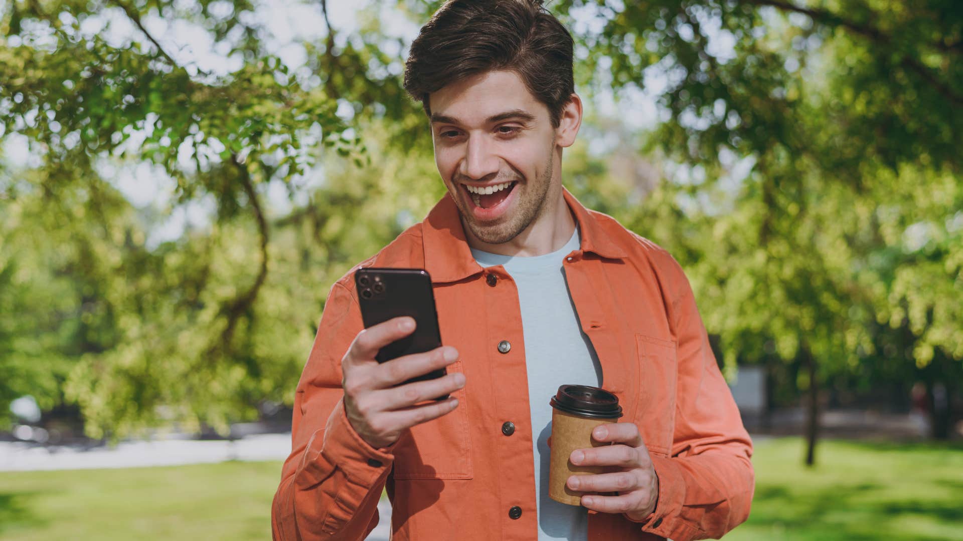 Man smiling and looking at synchronicities on his phone.
