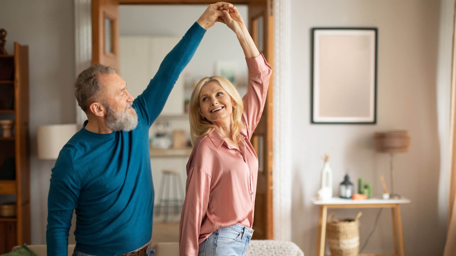 couple dancing in their living room smiling happily