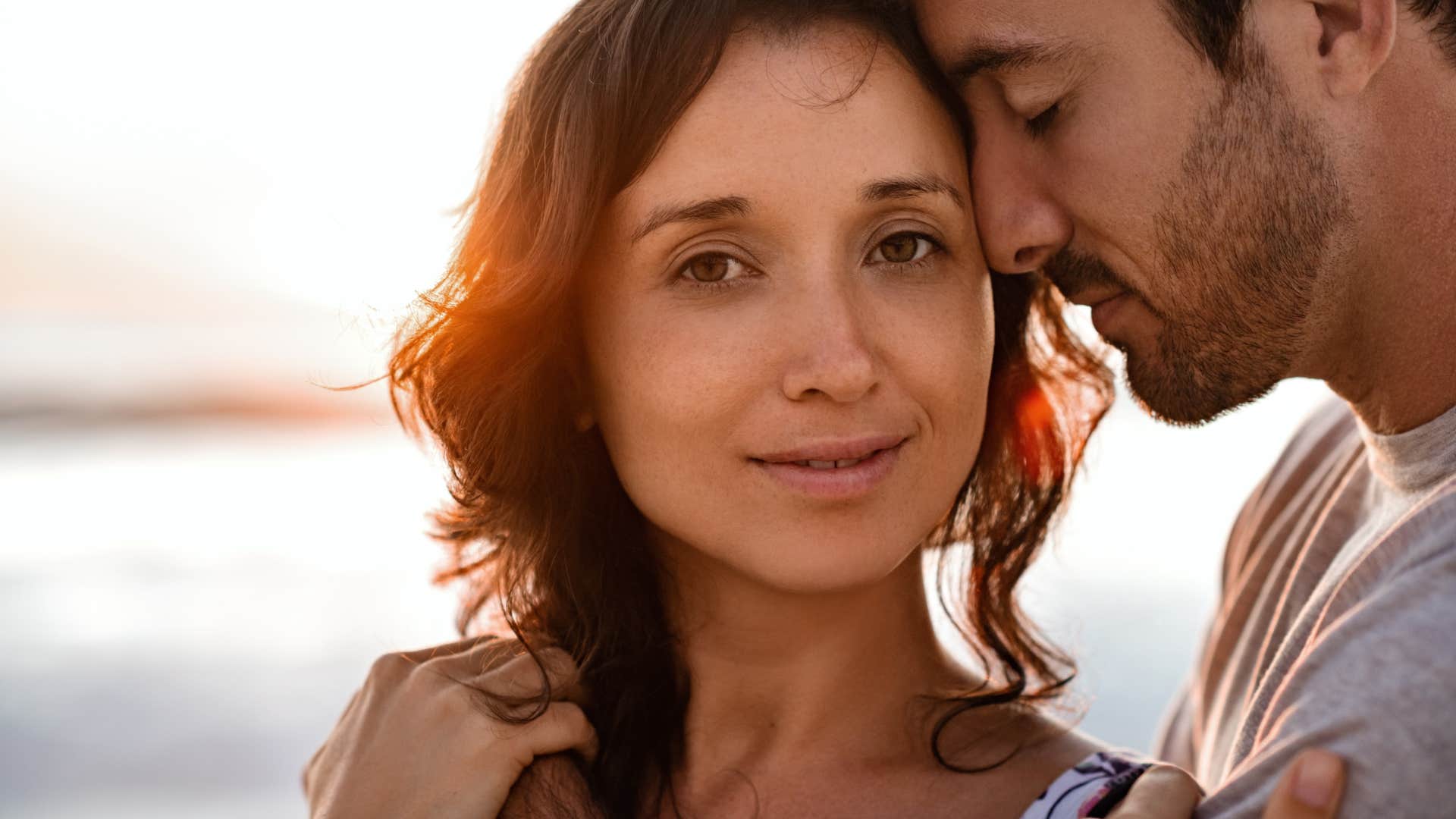 woman smiling as man leans on her lovingly