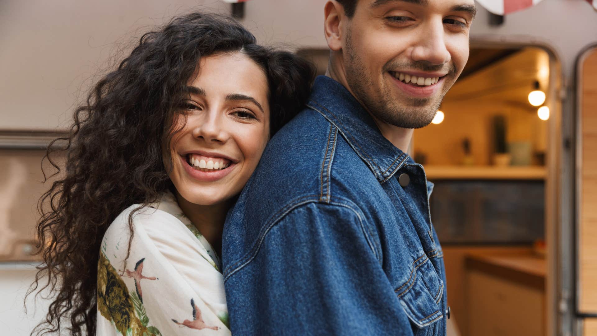 woman hugging man from behind smiling
