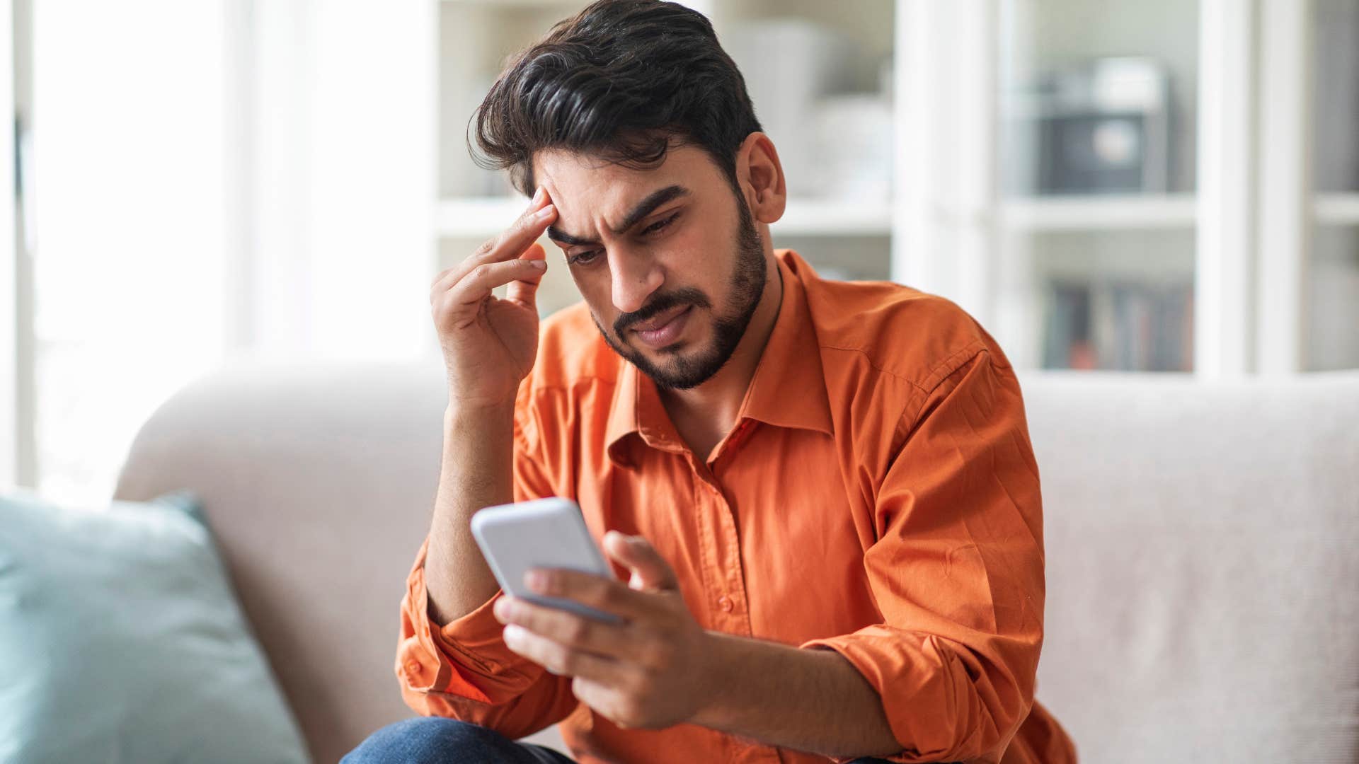 avoidant man looking upset on his phone
