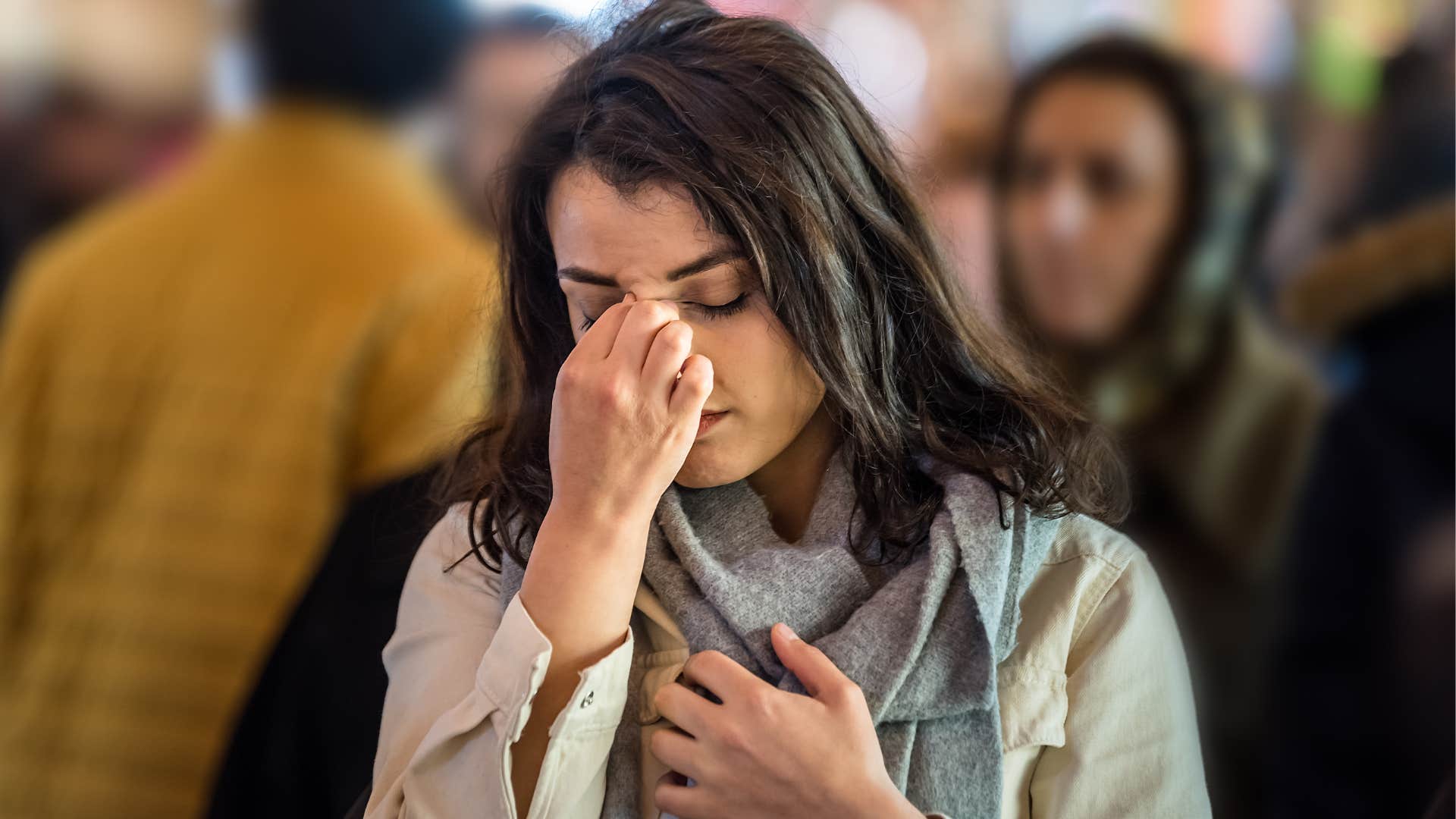 Woman feeling alone in crowds and holding her head.