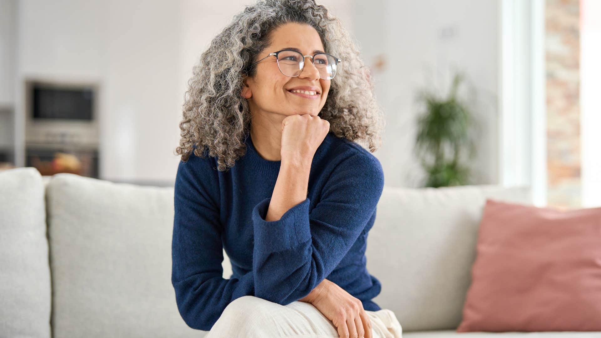 Woman who loves solitude smiling on her couch.