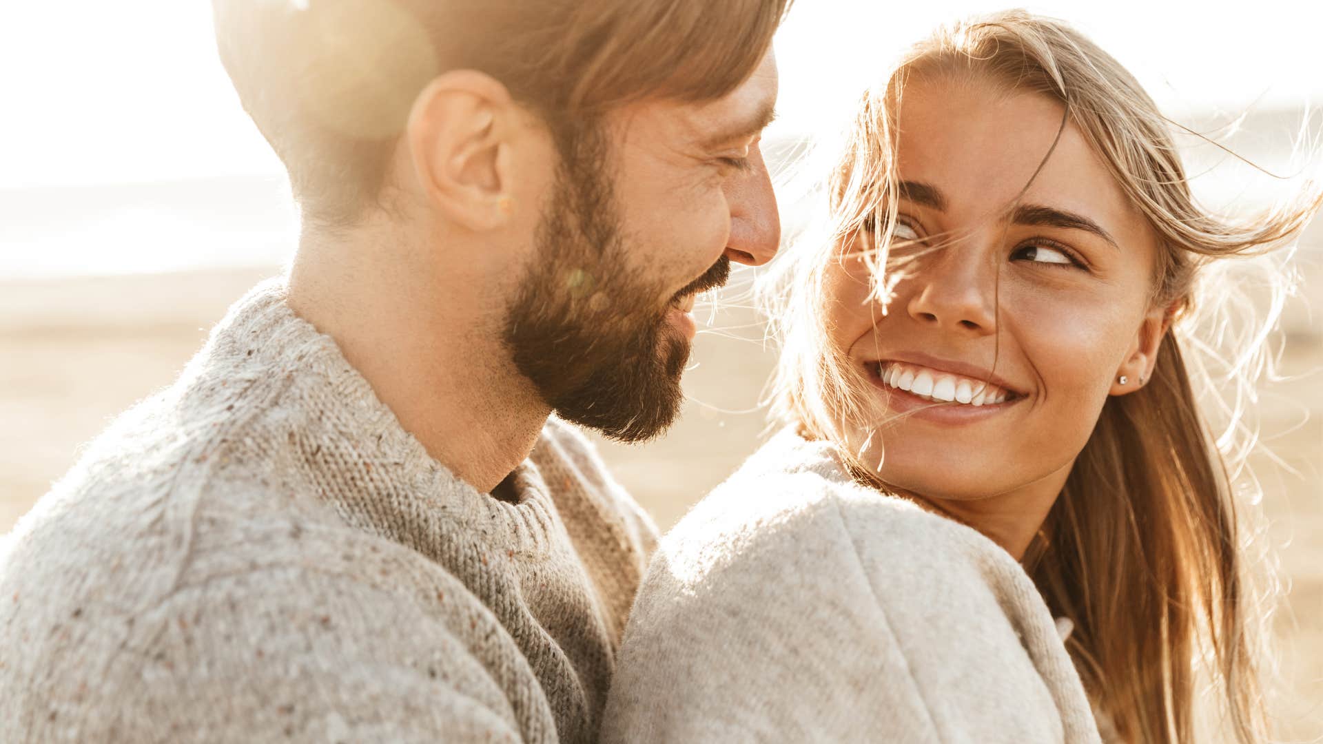 Woman who tries things her partner likes smiling on the beach.