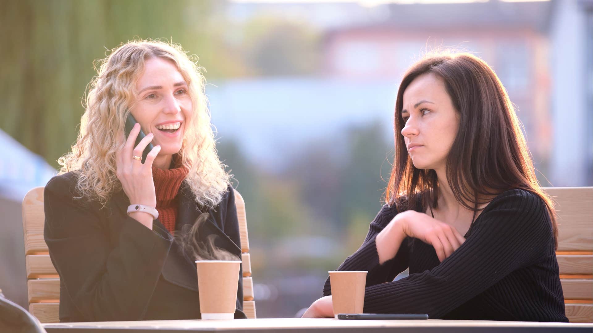 a woman keeps eye contact with her friend after being interrupted by her phone call
