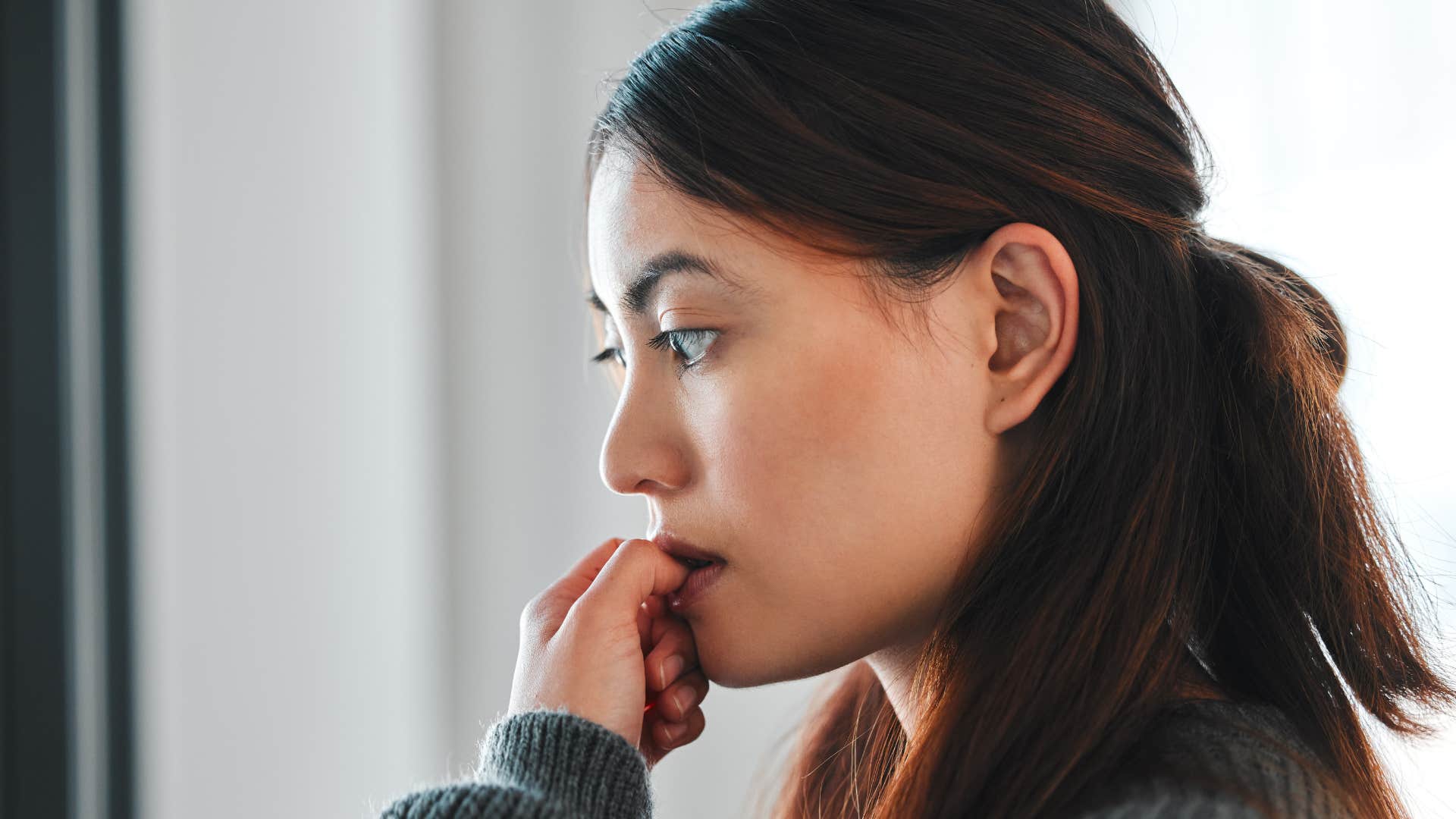 woman biting nails paranoid someone is watching her