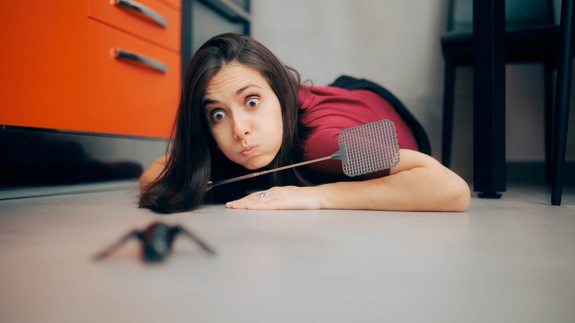 stressed woman chasing bug with a flyswatter