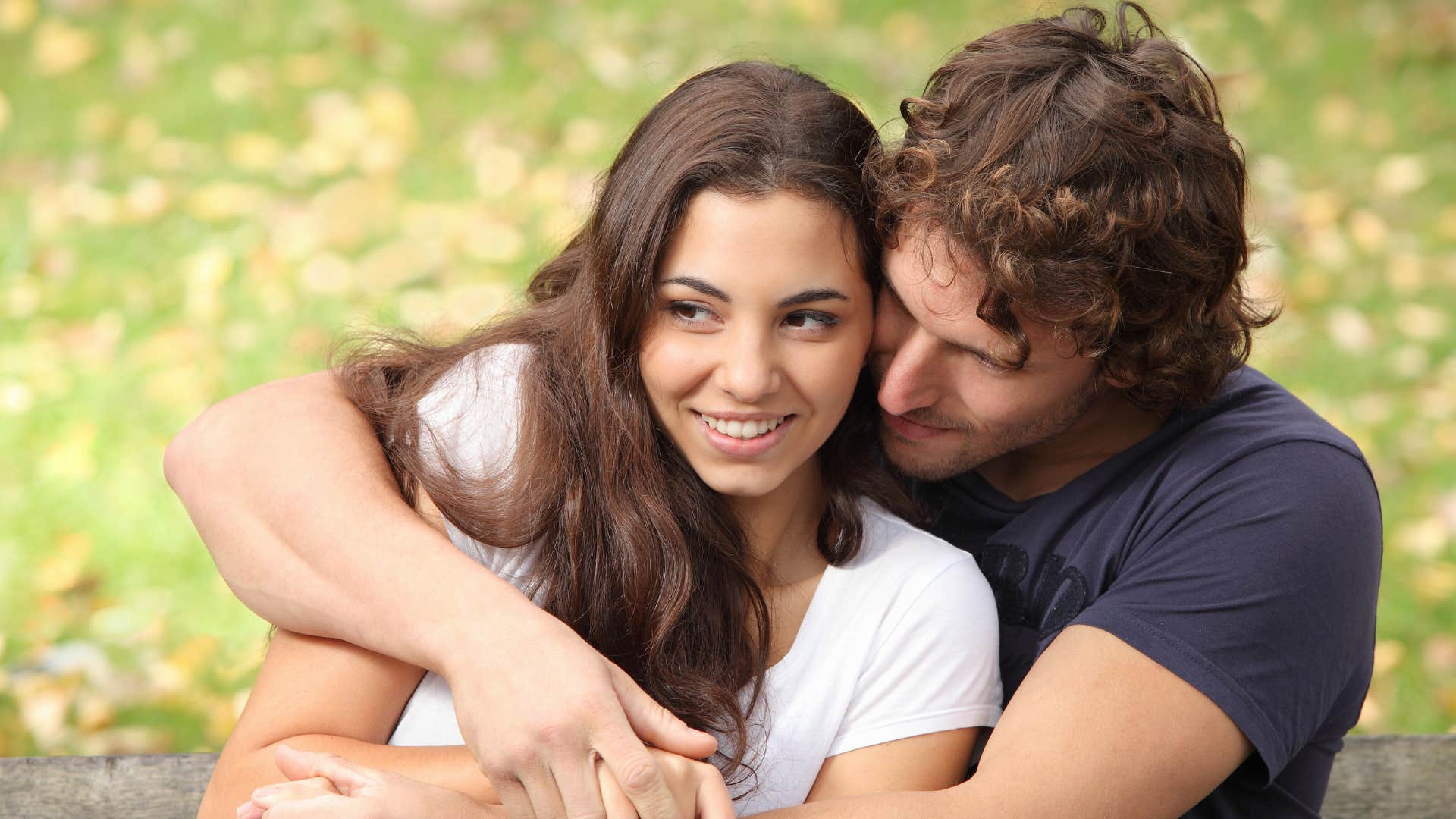 man in a protective stance sitting behind woman