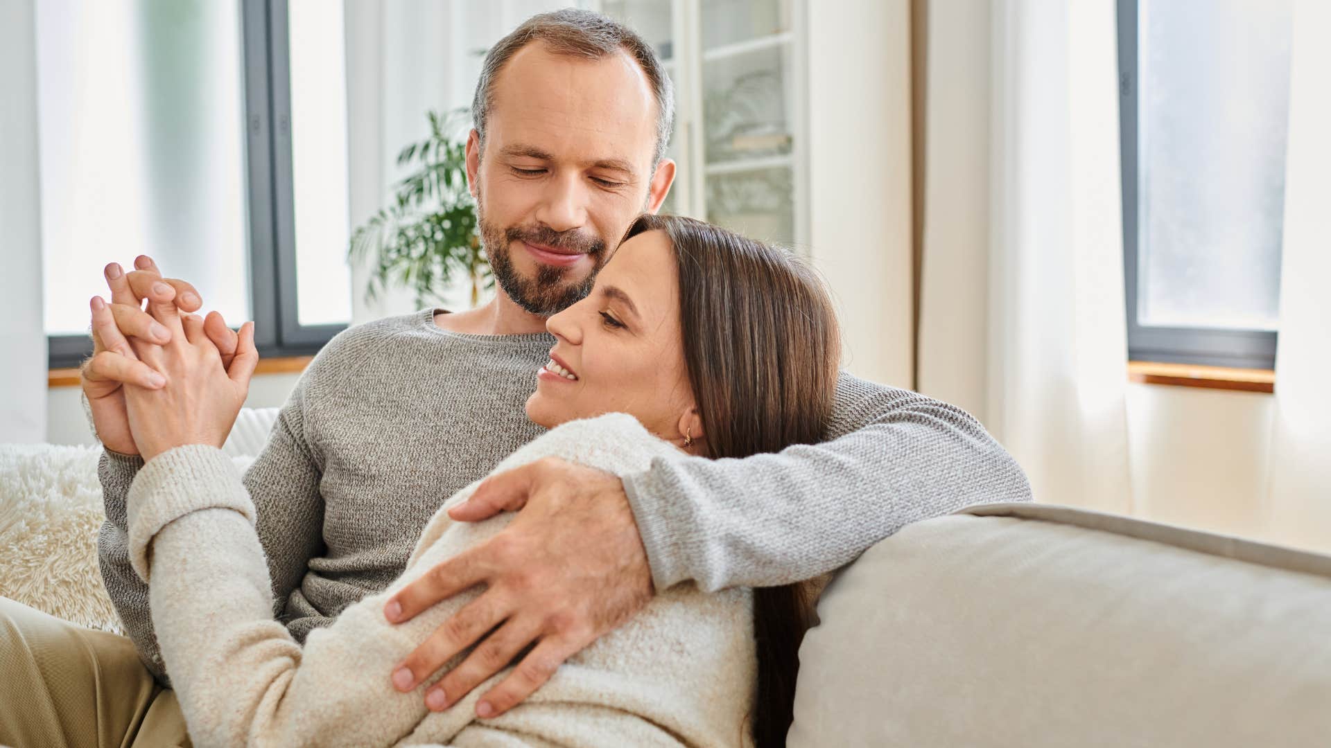 couple holding hands and snuggling on the couch as man jumps from relationship to relationship