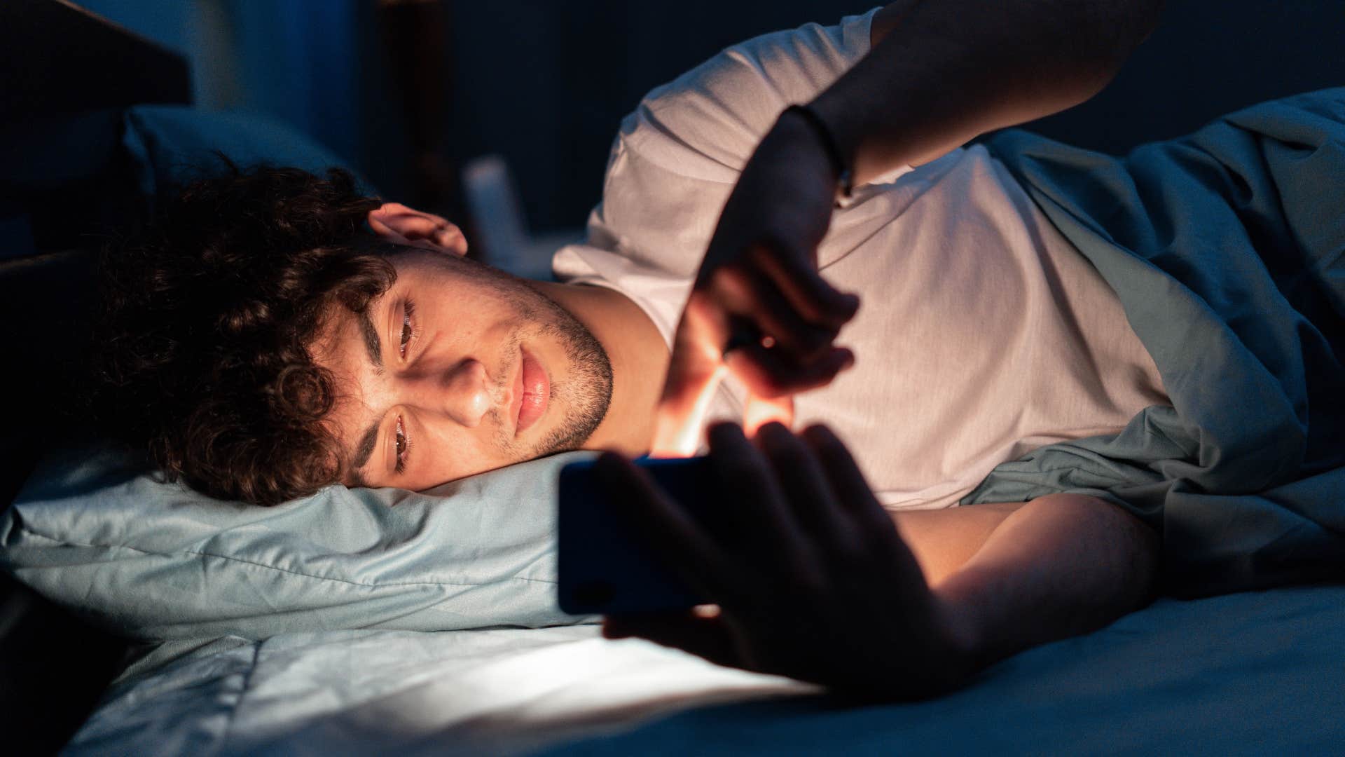 man in white shirt scrolling late at night as he watches exes every story