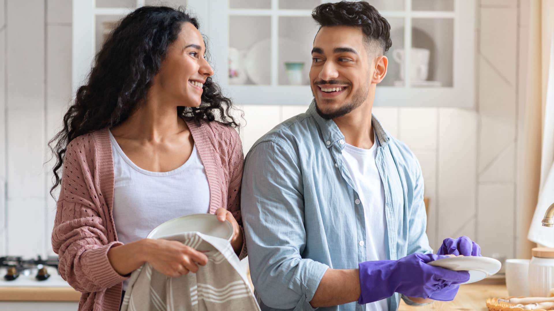 couple smiling sharing responsibilities washing dishes