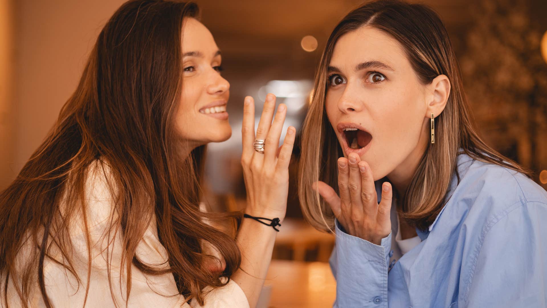 Two women smiling and spreading gossip or drama with each other.