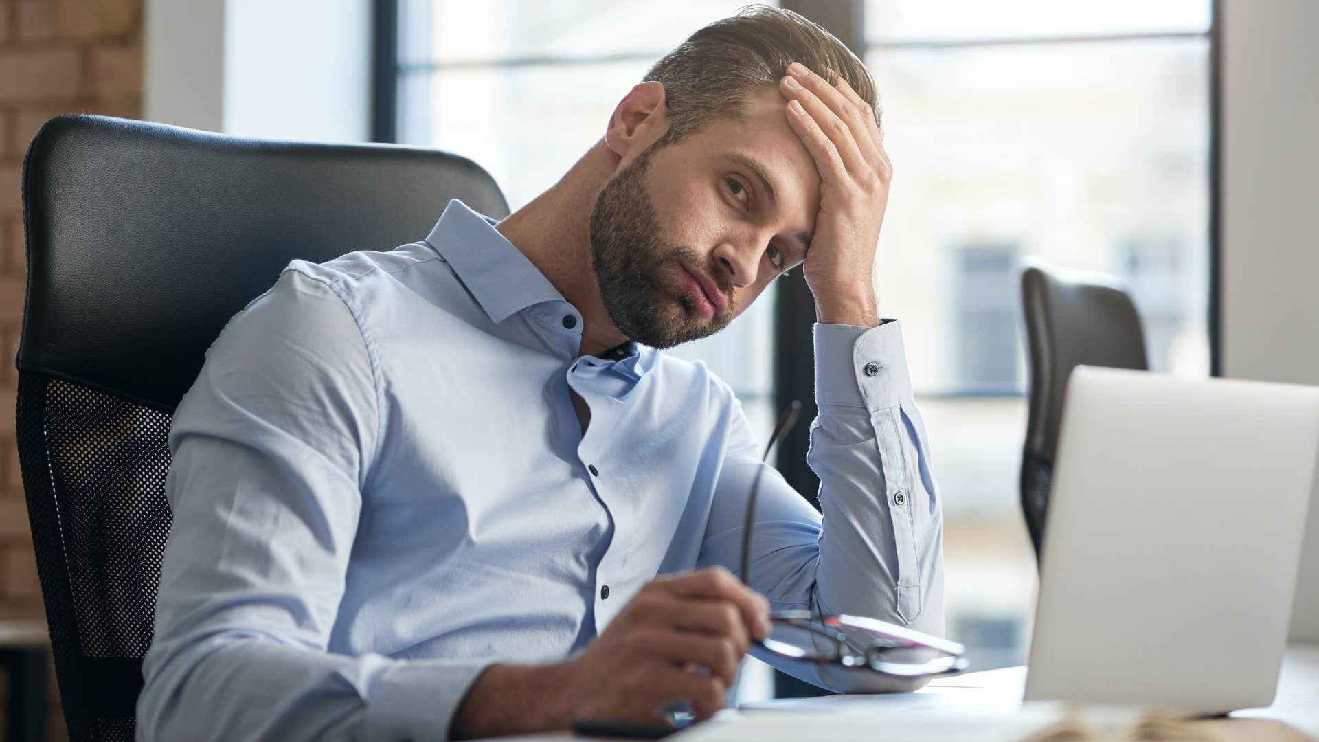 Man who's never asking for help looking tired at his desk.