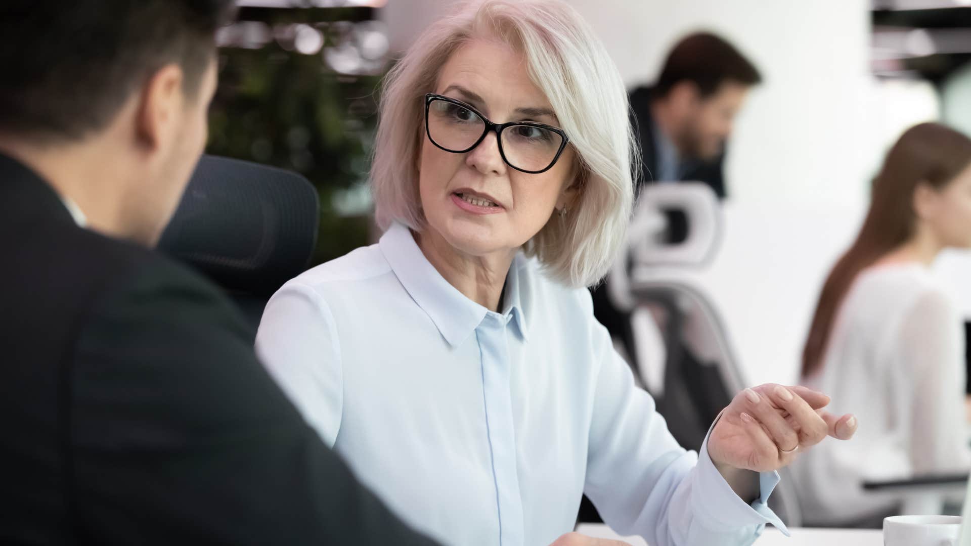 Woman blaming co-workers in a meeting with her boss.