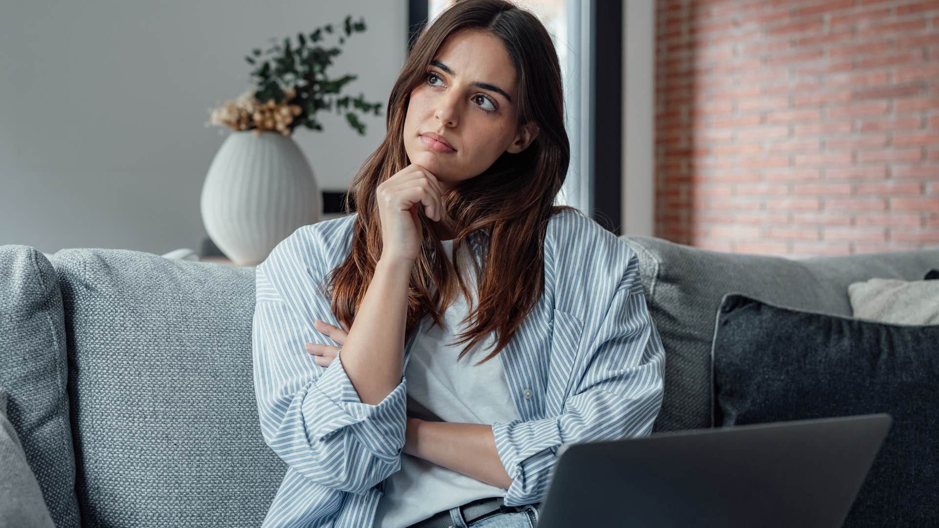 woman in a toxic work environment thinking while holding her laptop