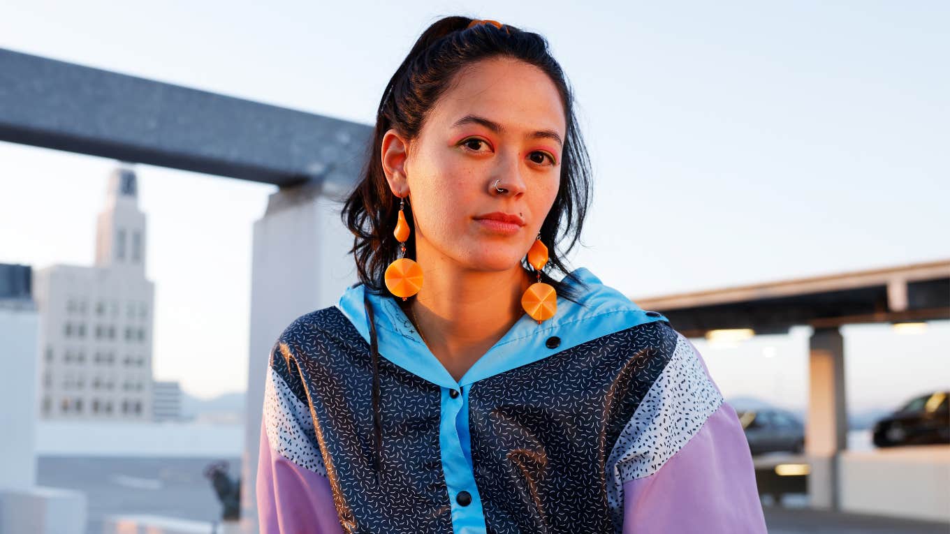 Things Gen Z Is Right About, Even If It Makes Boomers Mad gen z woman sitting outside in 80s colors