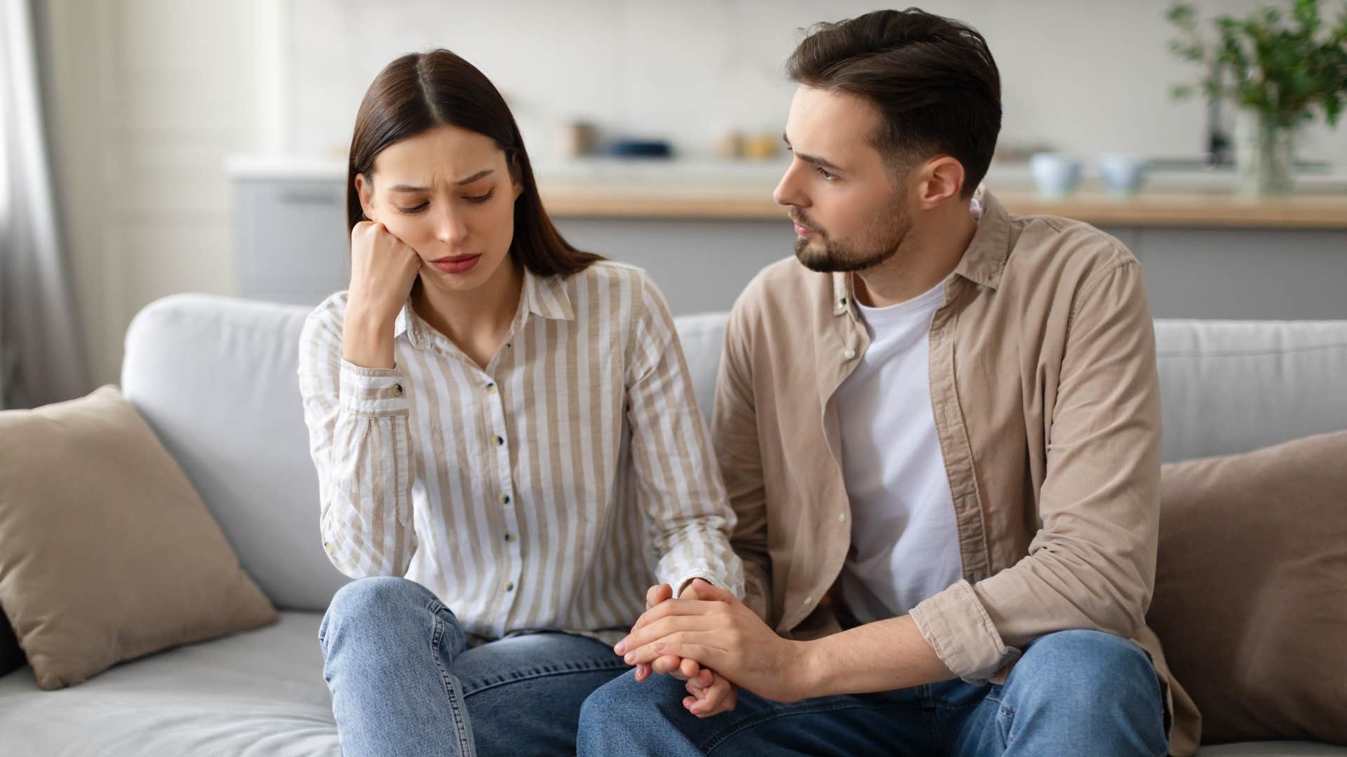 man empathetically holding womans hand comforting her