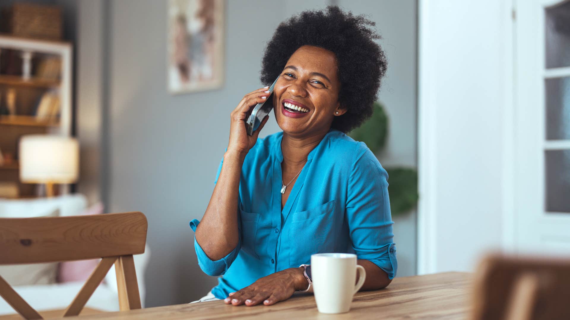 mom in blue shirt always on call as she smiles and happily takes to her adult children on the phone