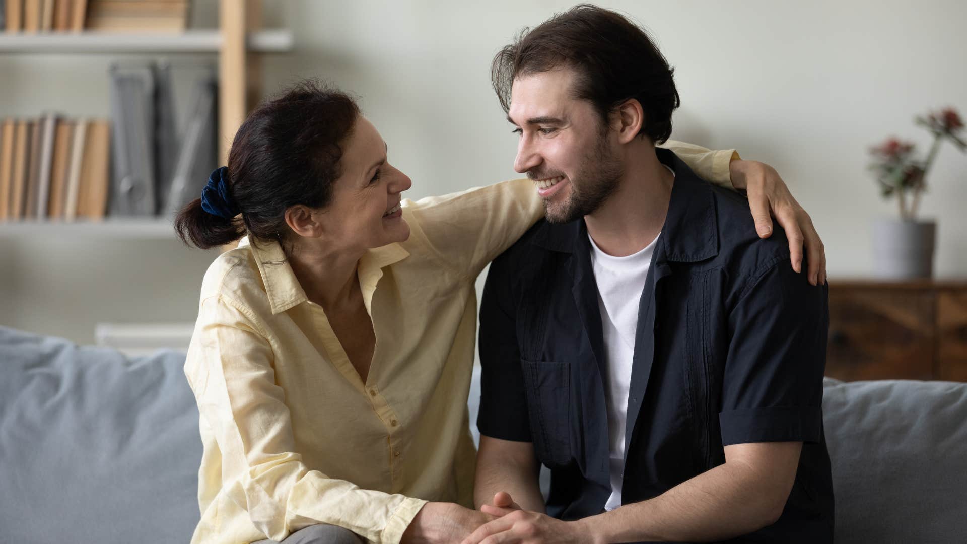 mom in yellow shirt respecting her son's need for privacy as she gives him a side hug and they both smile