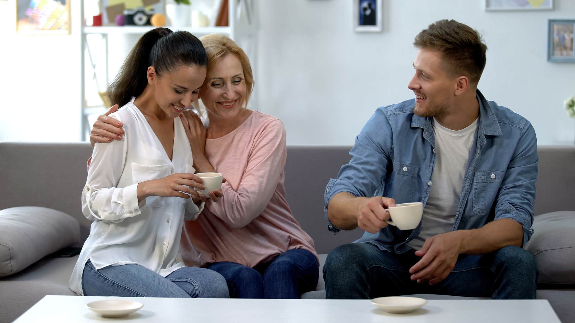 mom respecting the people her son cares about as she hugs his partner and her son enjoys tea