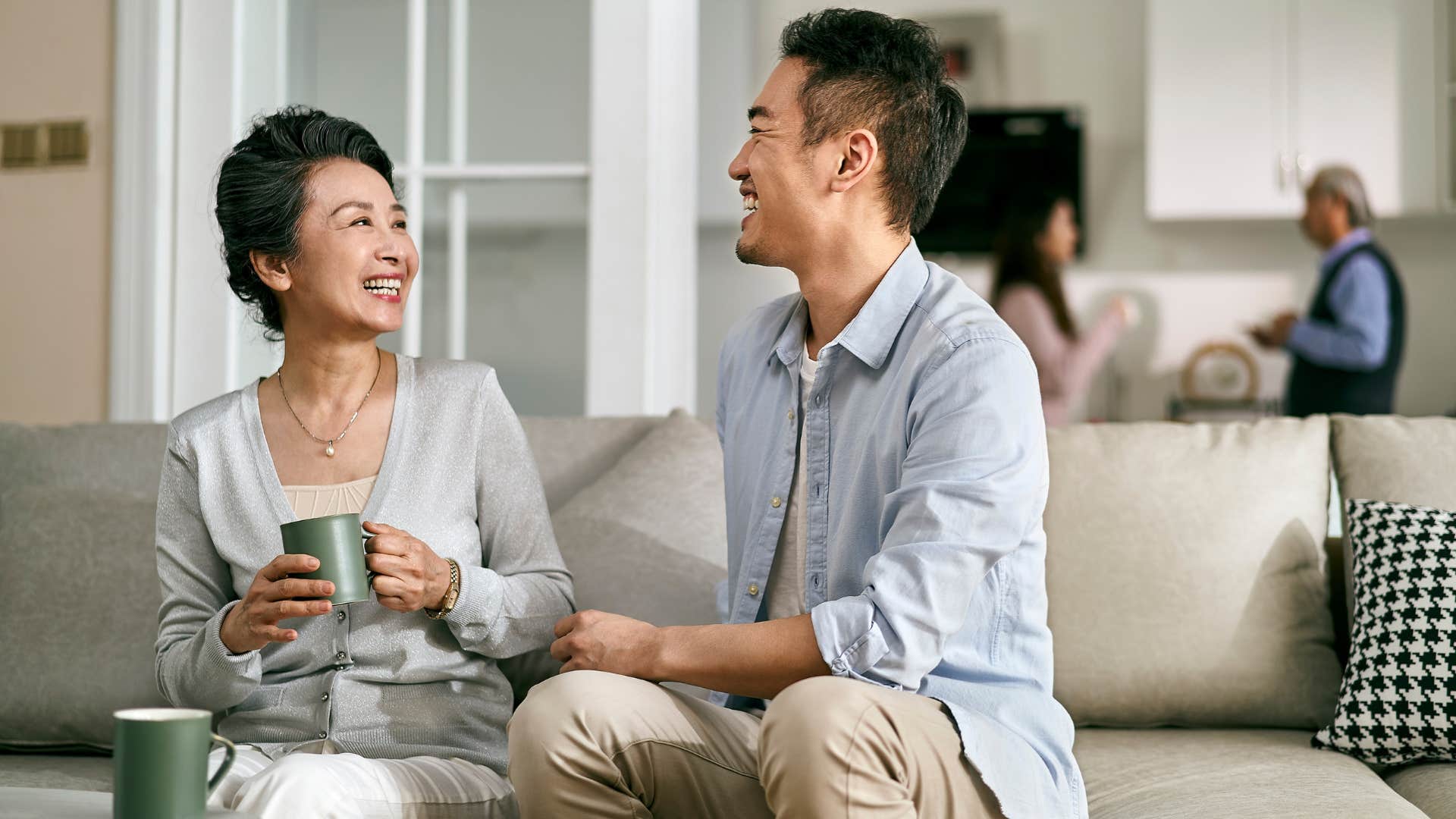 mom doing her best to spend time with her son as they both enjoy one another's company on the couch and mom drinks hot beverage