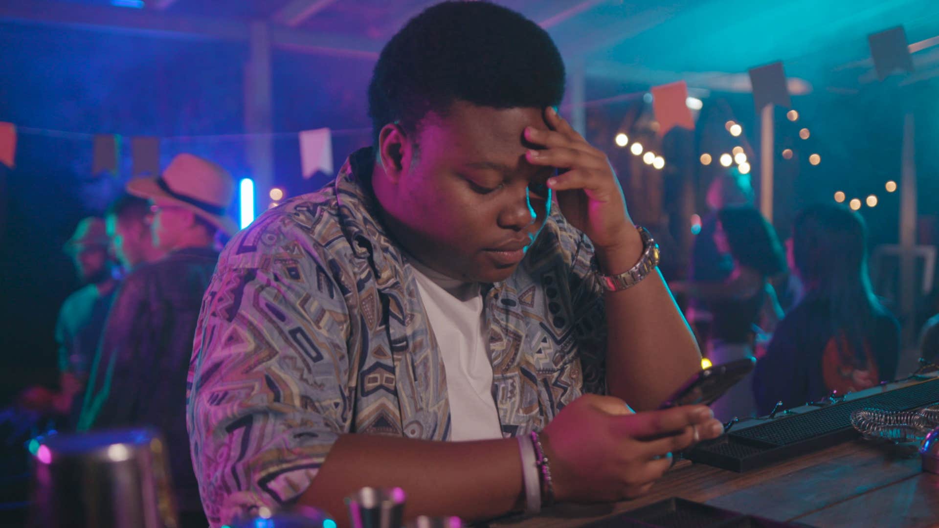man who dislikes going out on his phone in a club