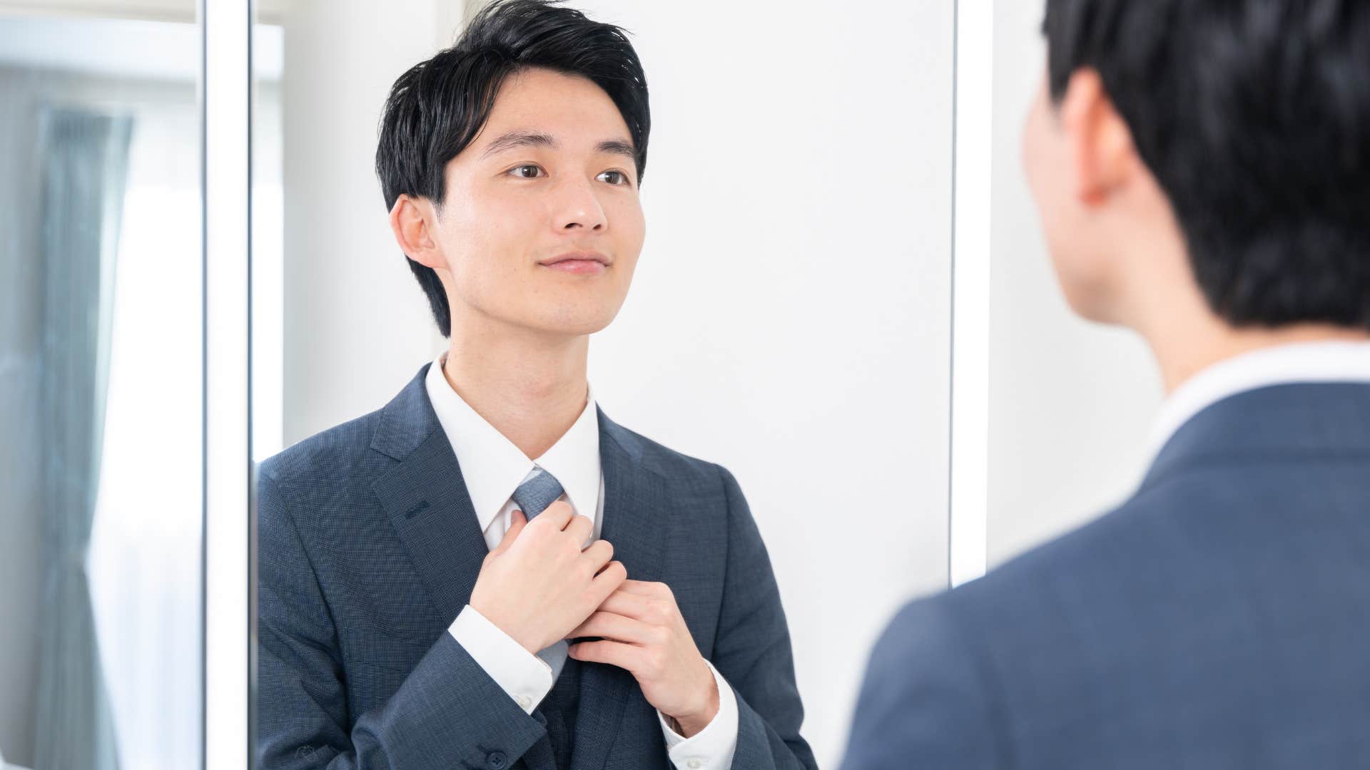 Man looks in bathroom mirror 
