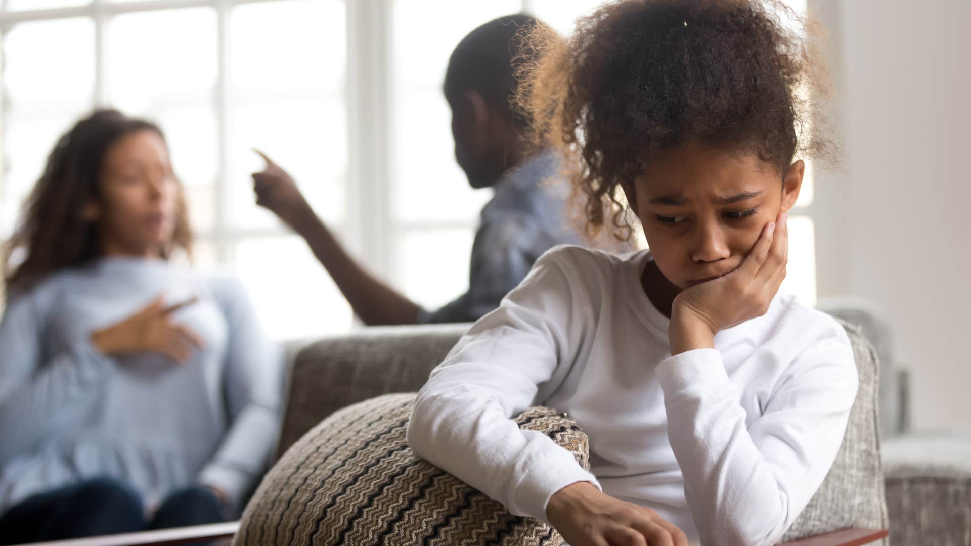 parents arguing behind daughter and dismissing her emotions