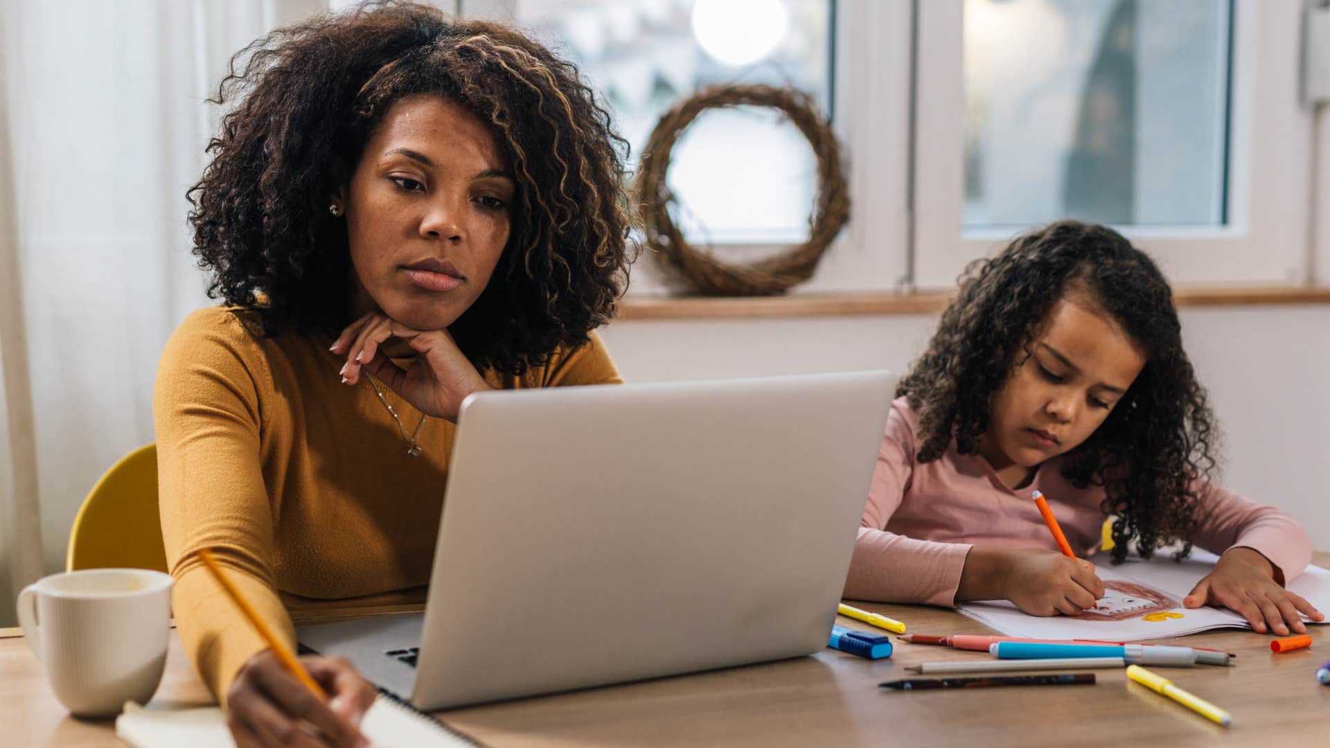 hardworking woman romanticizing burnout sitting next to young daughter