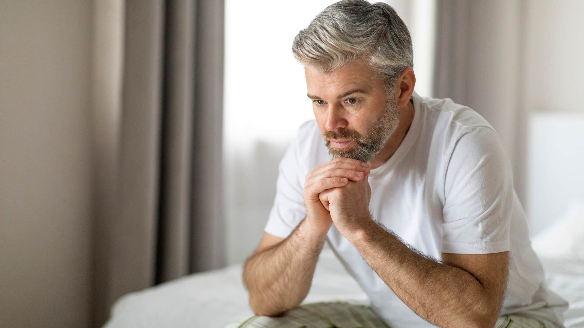 Man romanticizing burnout holding his head in his hands at home.