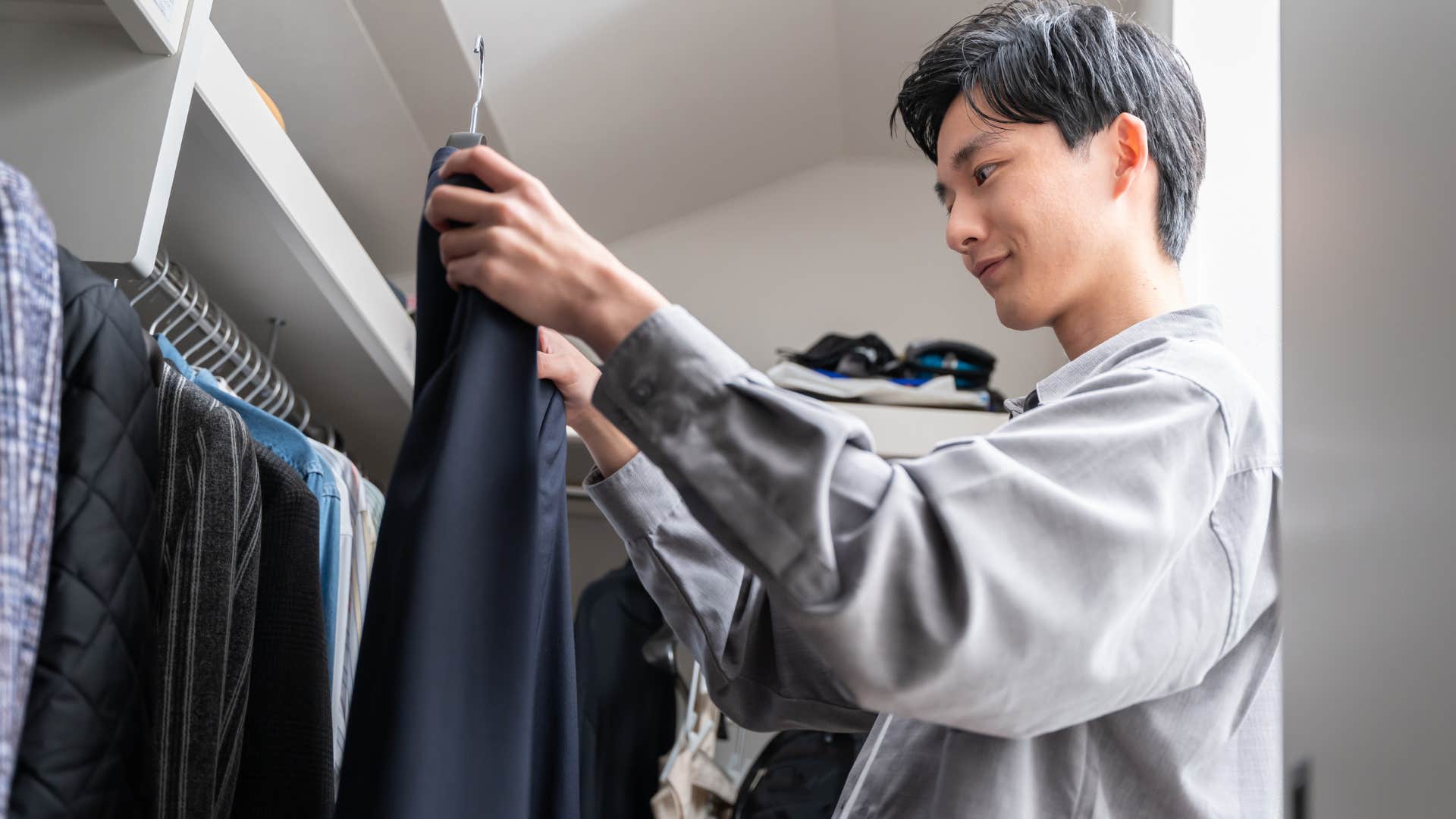 man looking through his seasonal wardrobe in his closet