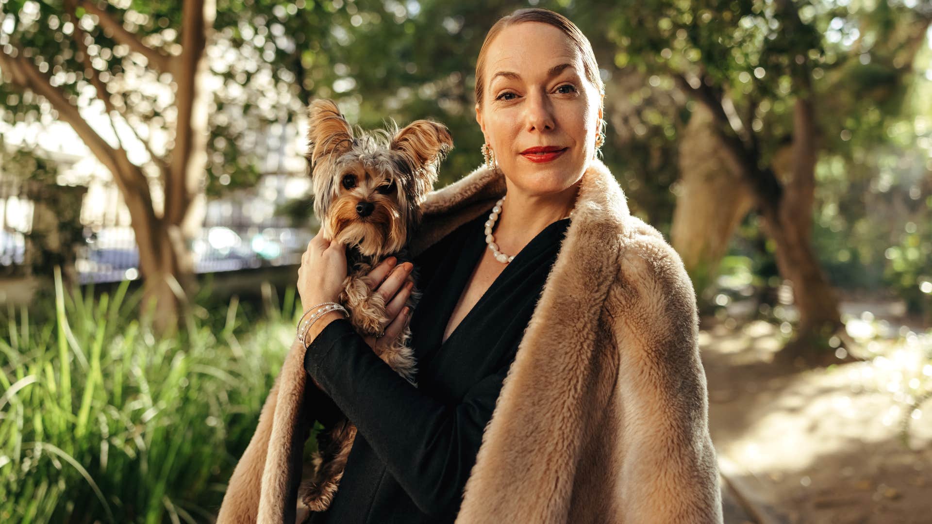 wealthy woman who splurges on her pets smiling holding dog