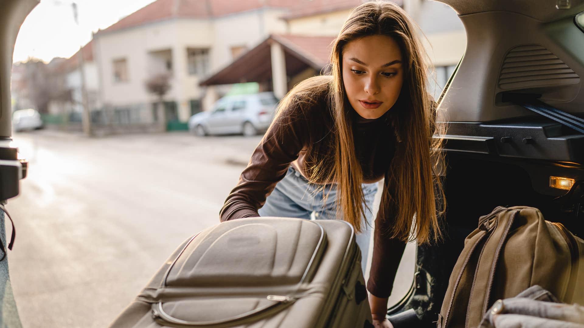 woman traveling impulsively putting suitcase in the car
