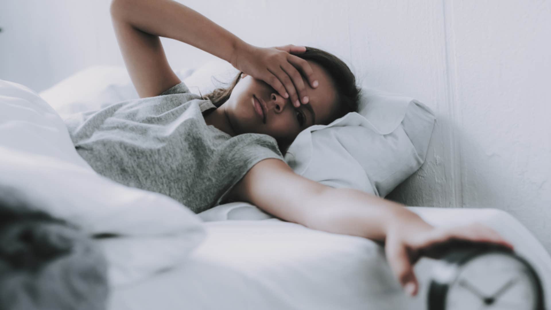 tired woman getting out of bed to attend plans she agreed to