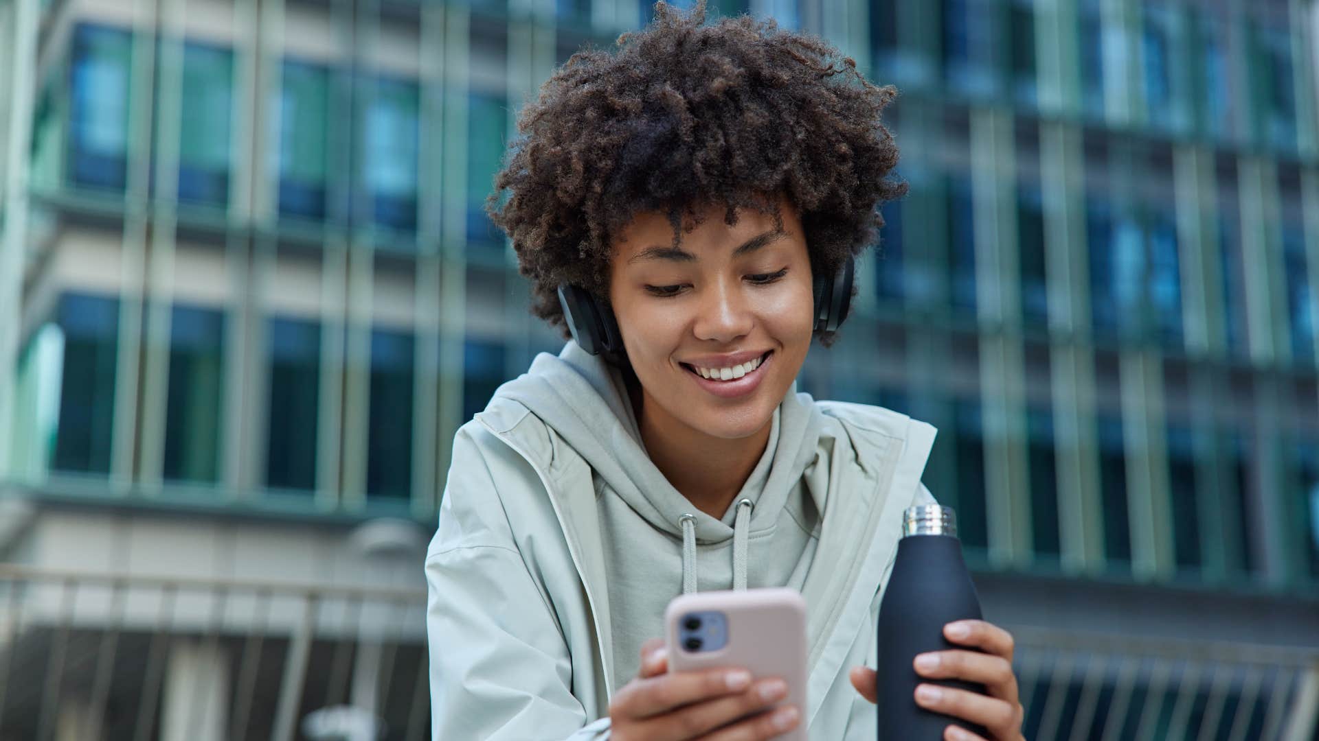 woman with gray jacket taking a break and doing a gym check-in while typing a motivational caption