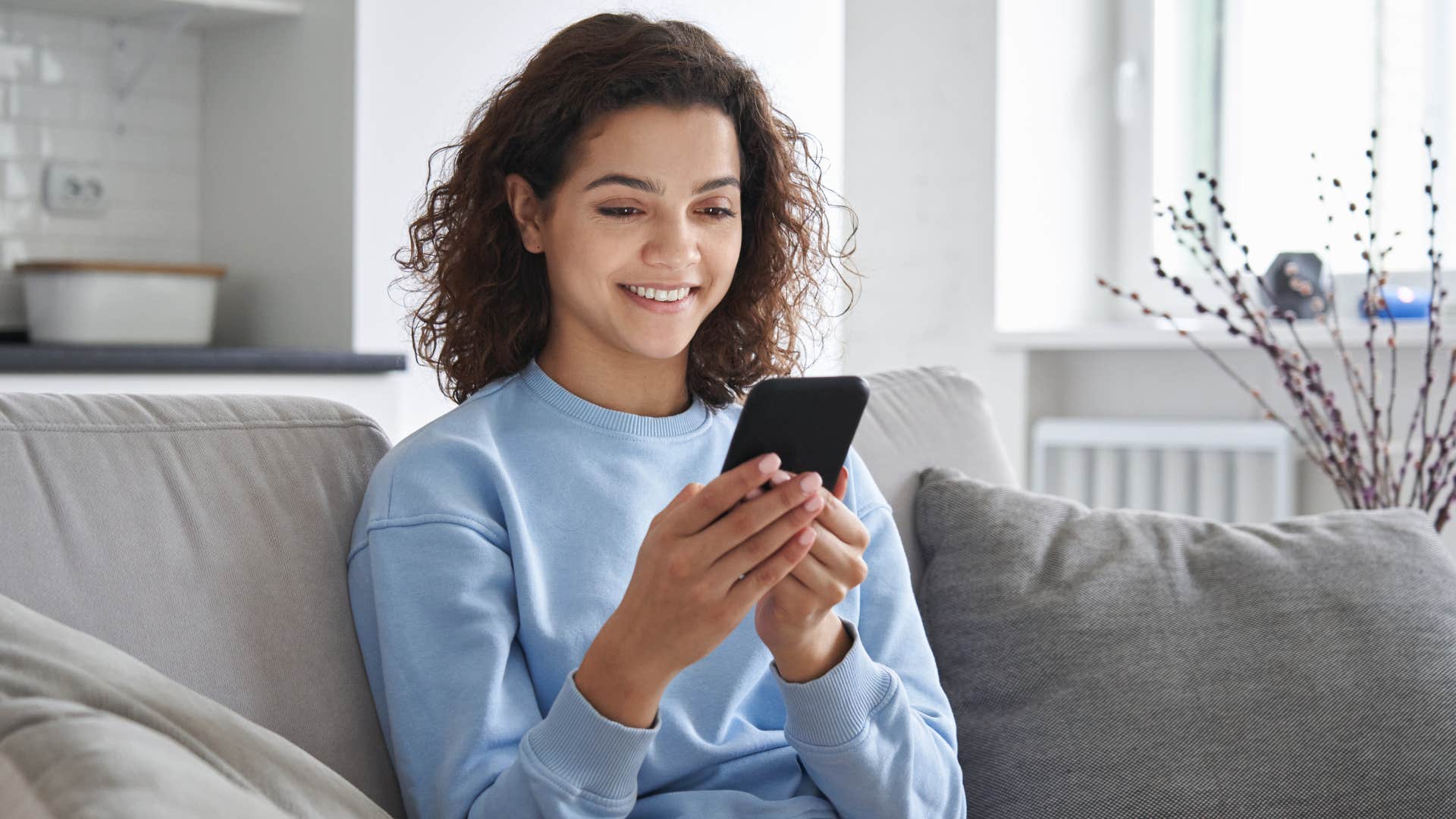 woman in light blue sitting on couch and typing out long captions