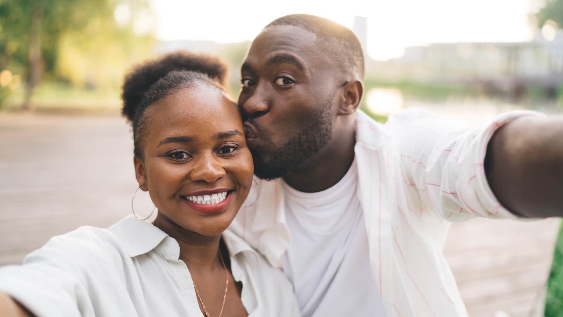 couple in white shirts taking a selfie outside as they post about their relationship